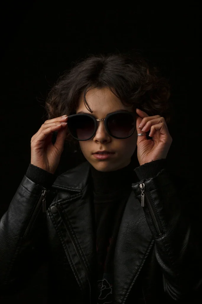 a woman wearing sunglasses and holding her sunglasses