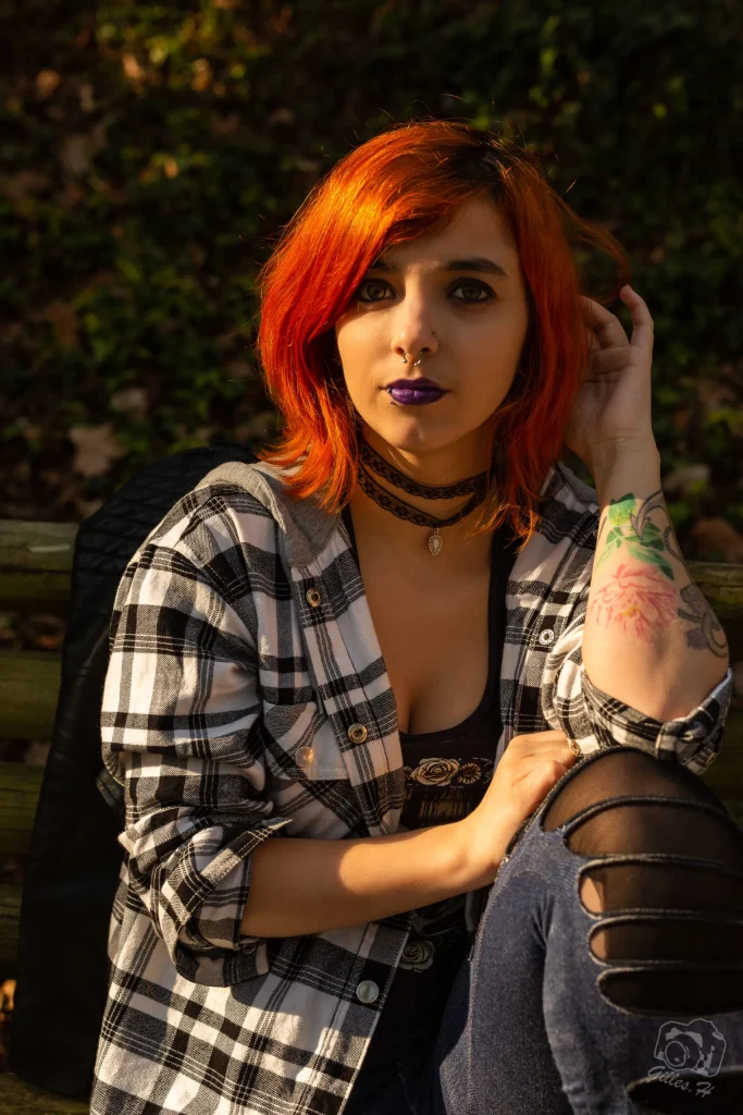 a woman with red hair and purple lipstick sitting on a bench